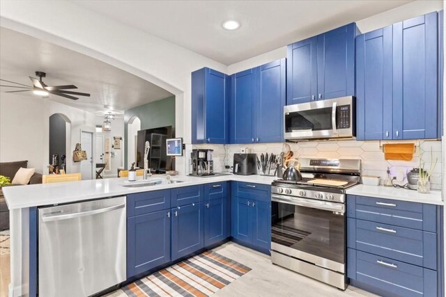 kitchen with decorative backsplash, blue cabinetry, kitchen peninsula, and appliances with stainless steel finishes