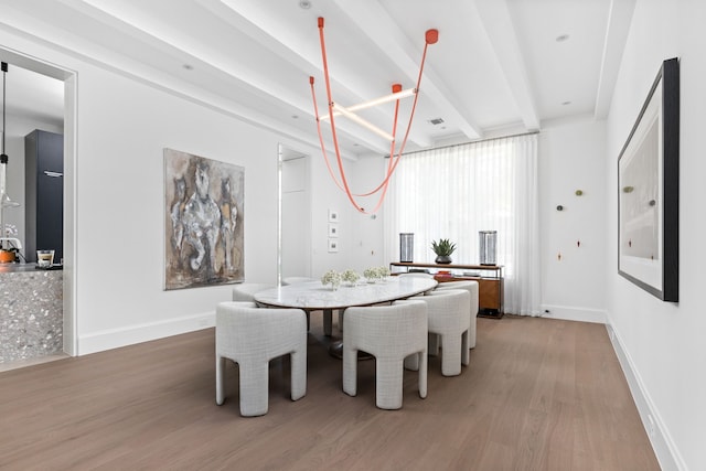 dining area featuring wood-type flooring and beam ceiling