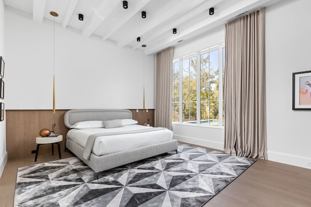 bedroom with wood-type flooring, wood walls, multiple windows, and beamed ceiling