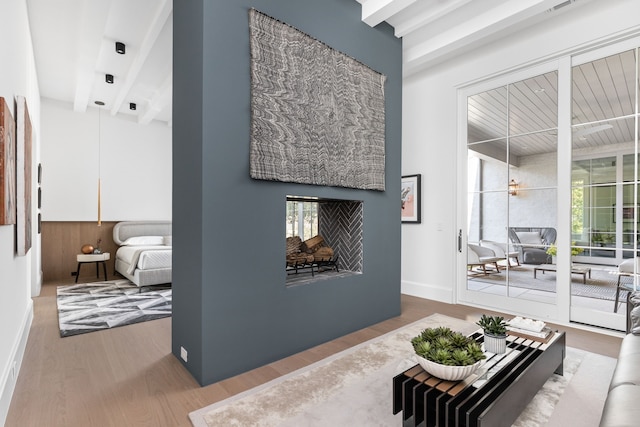 living room with a multi sided fireplace, hardwood / wood-style flooring, and beam ceiling