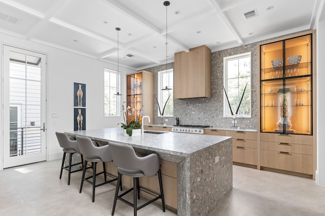 kitchen with a kitchen breakfast bar, range, an island with sink, decorative backsplash, and decorative light fixtures