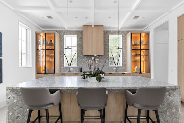 kitchen featuring coffered ceiling, pendant lighting, a kitchen breakfast bar, backsplash, and beamed ceiling