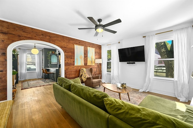 living room featuring ceiling fan, light hardwood / wood-style floors, and wooden walls