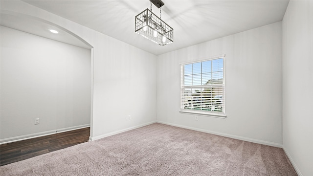 carpeted spare room featuring a chandelier