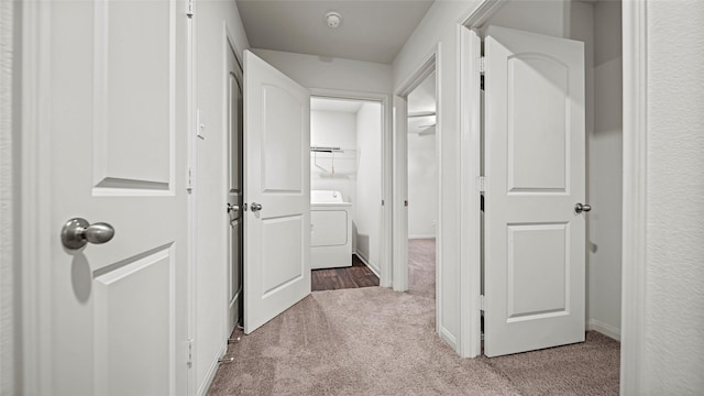 hallway with washer / clothes dryer and light carpet