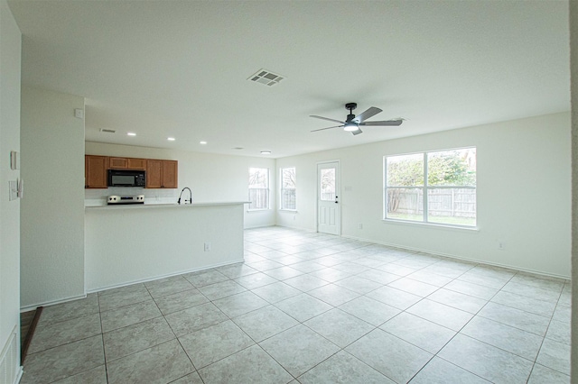 unfurnished living room featuring ceiling fan, light tile patterned floors, and sink