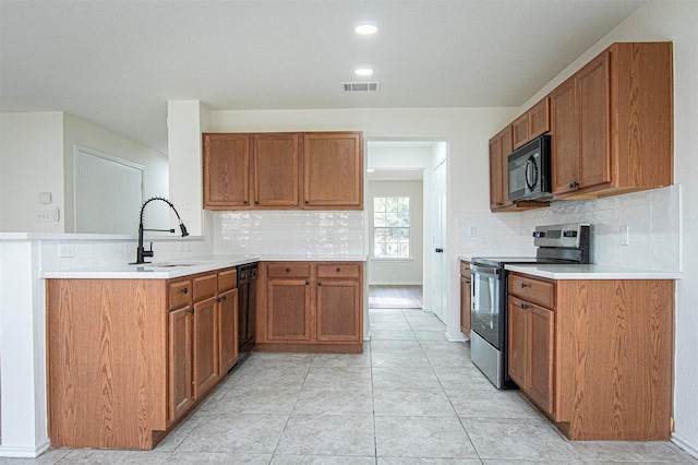 kitchen featuring kitchen peninsula, light tile patterned floors, black appliances, and sink