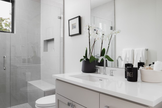 bathroom with toilet, a shower with shower door, and vanity