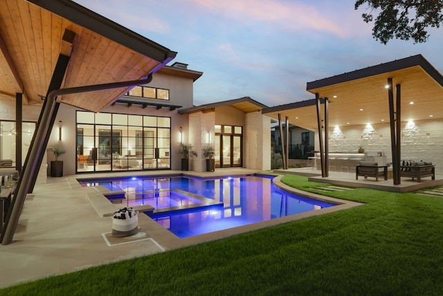 pool at dusk with a lawn and a patio area