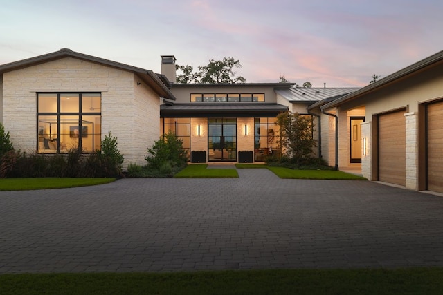 back house at dusk featuring a garage