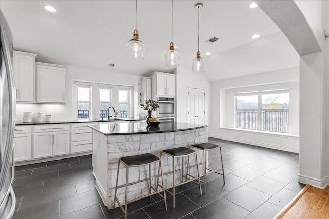 kitchen with lofted ceiling, white cabinets, a kitchen island, and pendant lighting