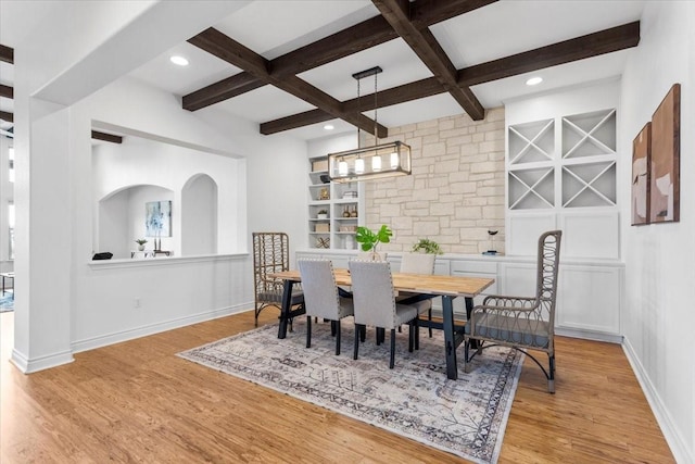 dining room featuring coffered ceiling, light hardwood / wood-style floors, beamed ceiling, and built in features