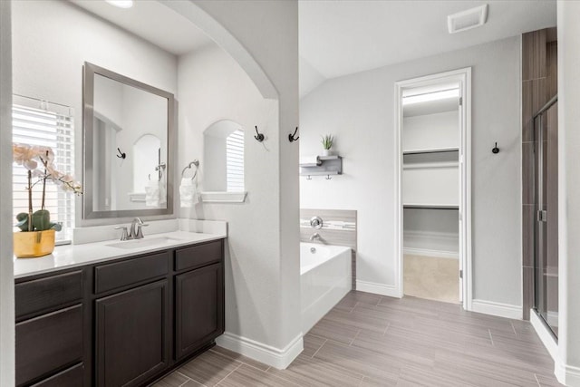 bathroom with independent shower and bath, lofted ceiling, and vanity