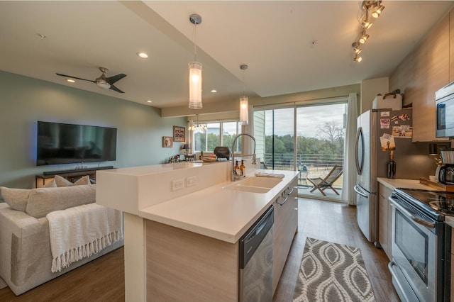 kitchen featuring hanging light fixtures, stainless steel appliances, a kitchen island with sink, ceiling fan, and sink