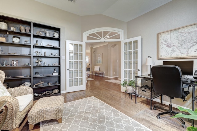 office space featuring french doors, vaulted ceiling, and light hardwood / wood-style flooring