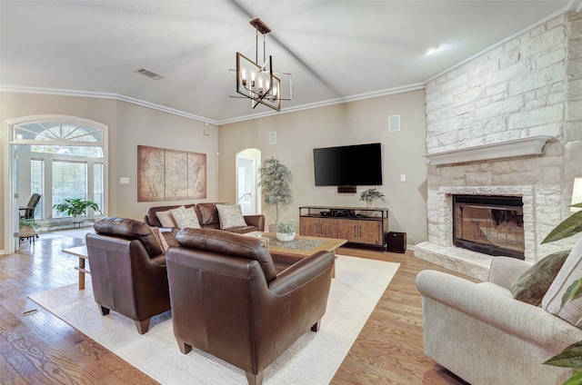 living room with a fireplace, ornamental molding, a notable chandelier, and light hardwood / wood-style flooring