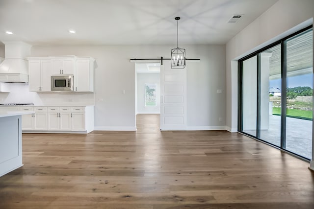 unfurnished dining area featuring a wealth of natural light, light hardwood / wood-style flooring, and a barn door