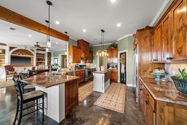 kitchen with a kitchen island with sink, appliances with stainless steel finishes, ceiling fan, stone countertops, and decorative light fixtures