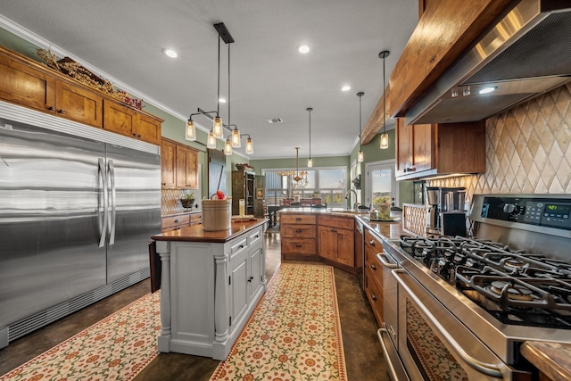 kitchen featuring kitchen peninsula, decorative light fixtures, stainless steel appliances, wall chimney range hood, and ornamental molding