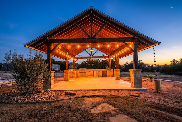 patio terrace at dusk with a gazebo and area for grilling