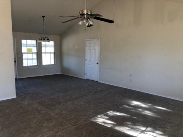 spare room with ceiling fan with notable chandelier, high vaulted ceiling, and dark carpet