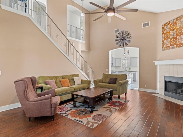 living room featuring a tiled fireplace, ceiling fan, high vaulted ceiling, and hardwood / wood-style flooring