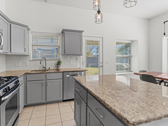 kitchen with appliances with stainless steel finishes, gray cabinetry, pendant lighting, sink, and tasteful backsplash