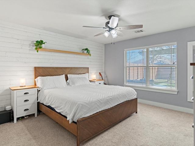 carpeted bedroom featuring wooden walls and ceiling fan