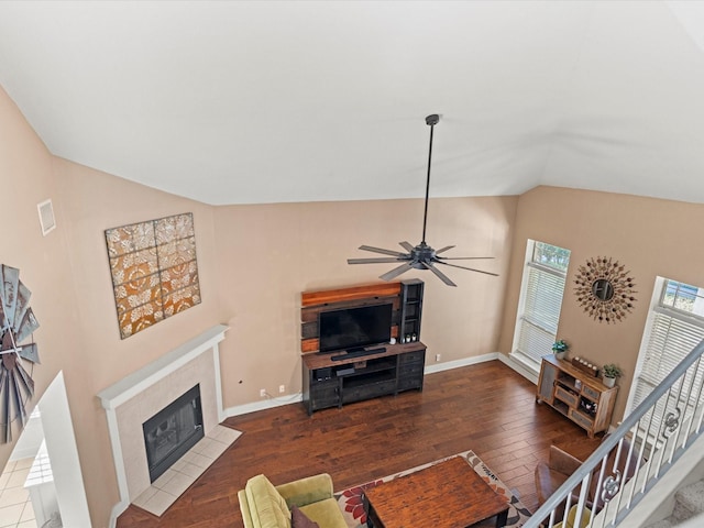 living room featuring lofted ceiling, a fireplace, ceiling fan, and dark wood-type flooring