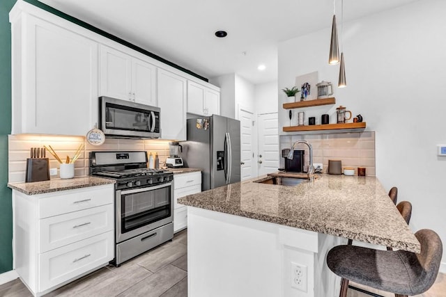 kitchen with sink, a breakfast bar area, white cabinetry, stainless steel appliances, and kitchen peninsula