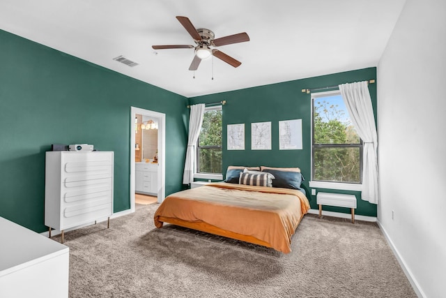 bedroom with multiple windows, ensuite bath, carpet floors, and ceiling fan