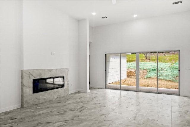 20714 Northland Dr, Lago Vista, TX 78645 - unfurnished living room featuring a high ceiling, a tiled fireplace, marble look tile flooring, and recessed lighting