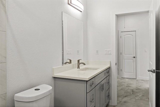 bathroom featuring toilet, marble finish floor, and vanity