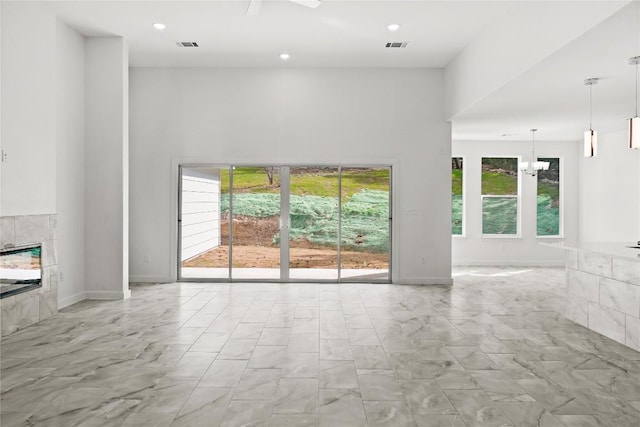 20714 Northland Dr, Lago Vista, TX 78645 - unfurnished living room with a tile fireplace, light marble finish floors, recessed lighting, a high ceiling, and a chandelier