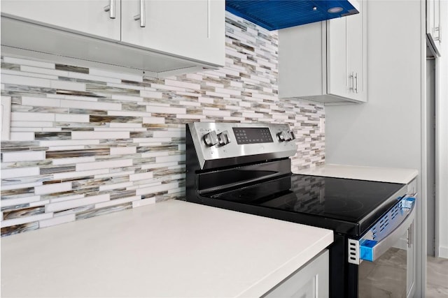20714 Northland Dr, Lago Vista, TX 78645 - kitchen featuring stainless steel electric range oven, decorative backsplash, exhaust hood, white cabinetry, and light countertops