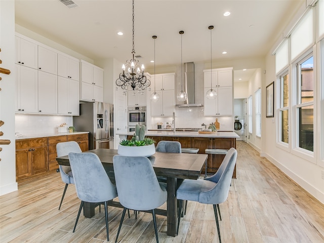 dining area with sink, a chandelier, and light hardwood / wood-style floors