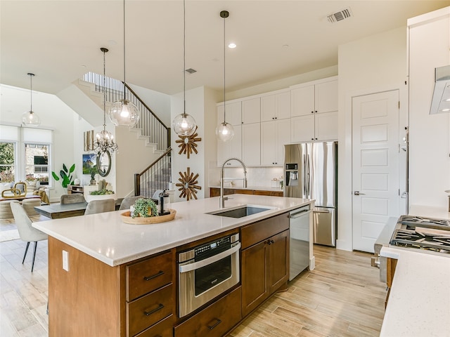 kitchen featuring stainless steel appliances, a kitchen island with sink, pendant lighting, and sink