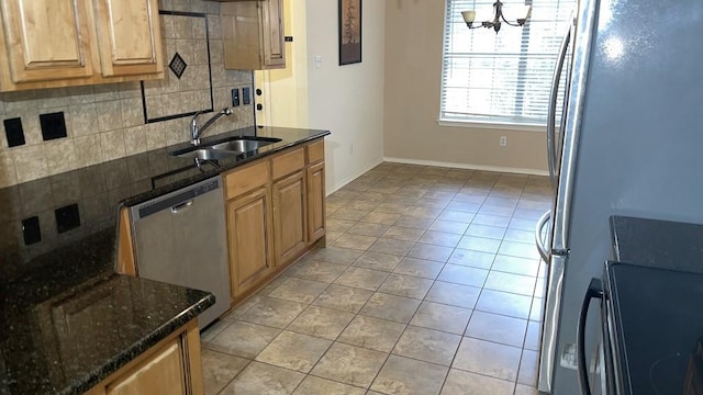 kitchen with dark stone countertops, stainless steel appliances, decorative backsplash, sink, and an inviting chandelier