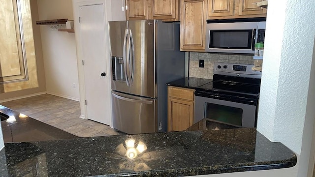 kitchen with stainless steel appliances, decorative backsplash, light tile patterned floors, and dark stone counters