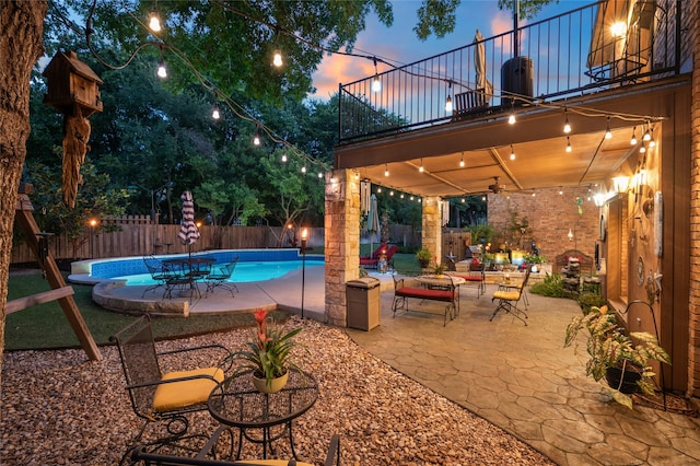 pool at dusk with a patio area