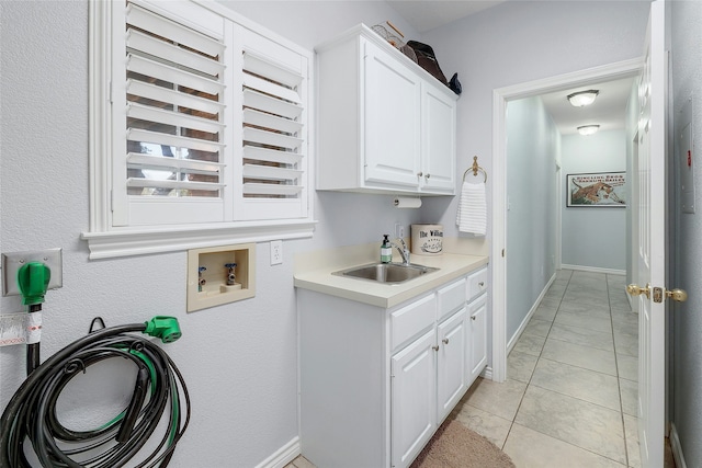 washroom featuring sink, washer hookup, light tile patterned floors, and cabinets