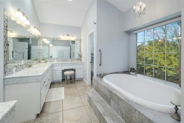 bathroom with tiled bath, vaulted ceiling, tile patterned flooring, backsplash, and vanity