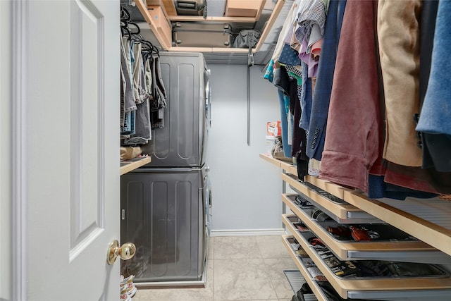 spacious closet featuring stacked washer / dryer and light tile patterned floors