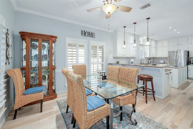 dining room with ornamental molding, ceiling fan, light wood-type flooring, and sink