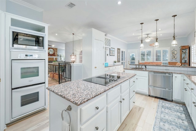 kitchen featuring stainless steel appliances, decorative light fixtures, white cabinetry, and a center island