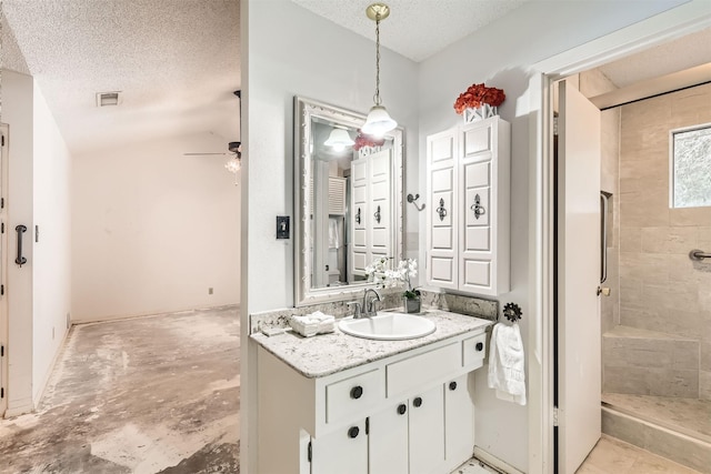 bathroom with a textured ceiling, a shower, ceiling fan, and vanity