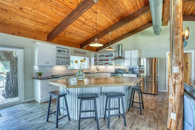 kitchen featuring white cabinetry, backsplash, wall chimney range hood, pendant lighting, and appliances with stainless steel finishes