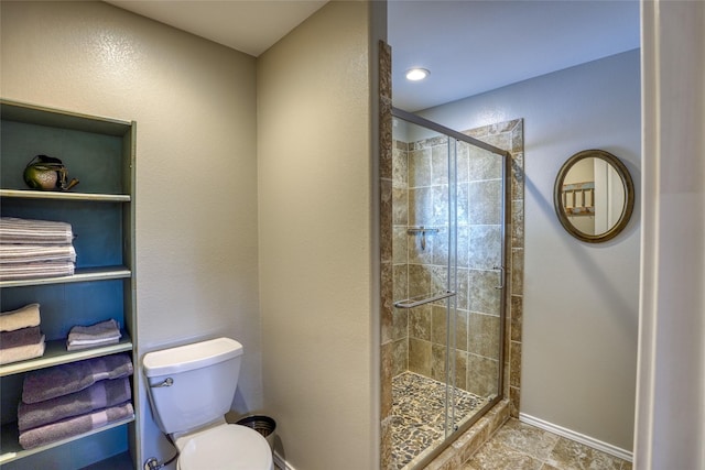 bathroom with a shower with shower door and toilet