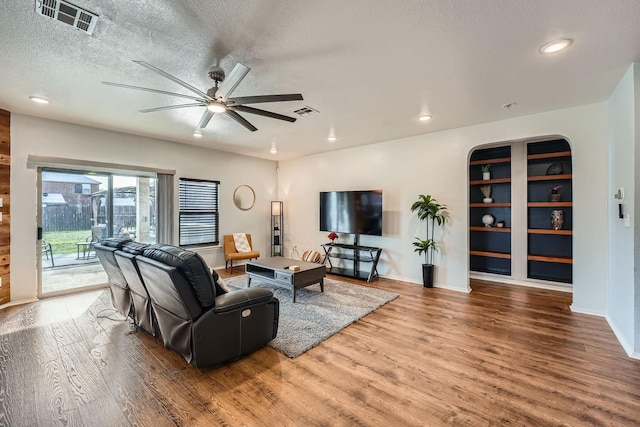 living room featuring wood-type flooring, a textured ceiling, and ceiling fan