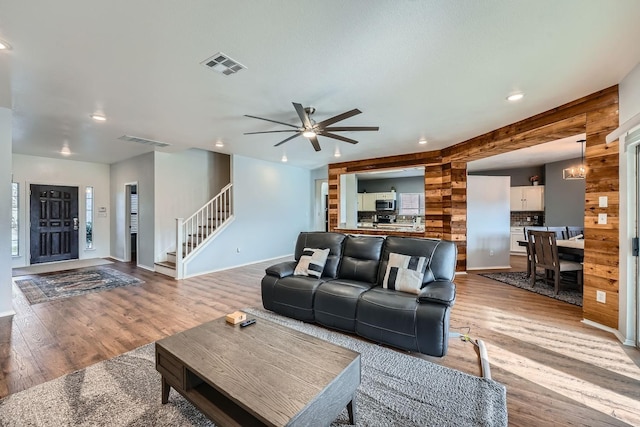 living room featuring ceiling fan with notable chandelier and wood-type flooring